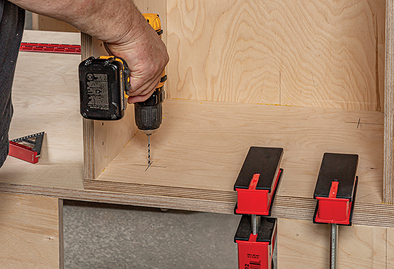 drilled two holes through the cabinet top and the sub-top and installed flanged threaded inserts in the cabinet tops.